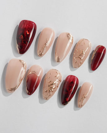 Gilded Rouge nail set with warm burgundy amber base and raised metallic gold leaf detail