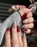 Gilded Rouge in short almond shape with burgundy amber nails and embossed gold leaf