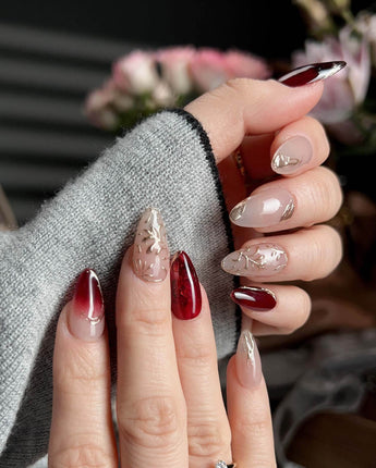 Gilded Rouge in short almond shape with burgundy amber nails and embossed gold leaf