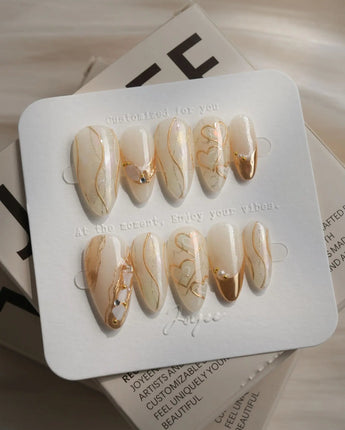 Gilded Truth press-on nails in medium almond shape — Minimalist Aurora White, Gold Metallic Outlines & Heart Illustrations.