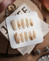 Gilded Truth press-on nails in medium coffin shape — Minimalist Aurora White, Gold Metallic Outlines & Heart Illustrations.