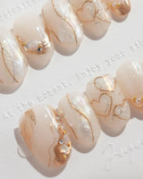 Gilded Truth nail art close-up showing Minimalist Aurora White, Gold Metallic Outlines & Heart Illustrations. details