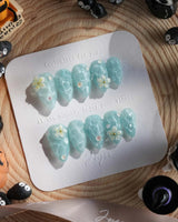 Glass Sea short stiletto nails with aqua cat-eye waves and 3D floral accents