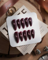 Glint Plum press-on nails in medium stiletto shape — deep plum cat eye shimmer