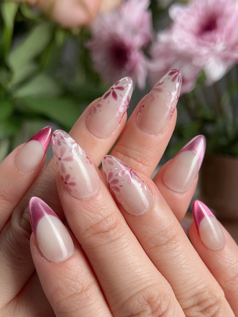 Glow Garden handmade press-on nails featuring magenta cat eye finish with French tips and hand-painted floral designs on short almond shape