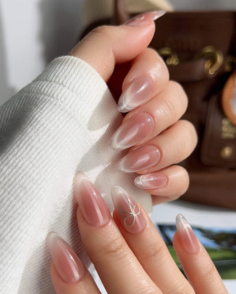 Almond-shaped French ombre press-on nails with gold bow

