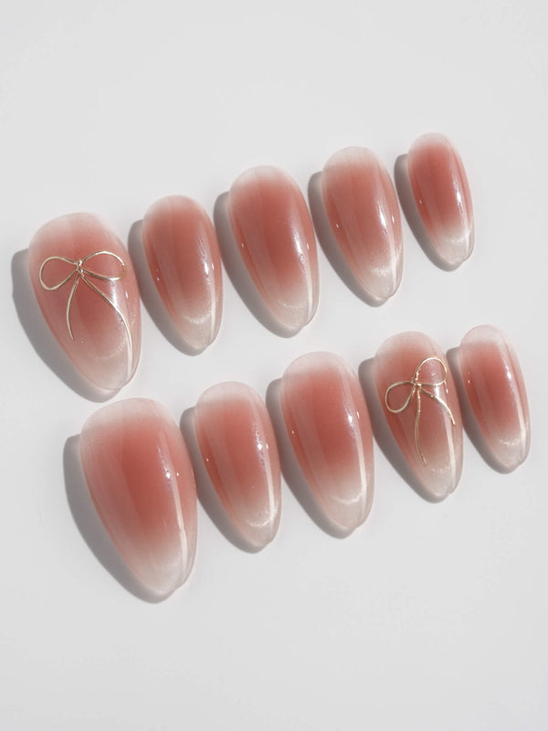 Sheer nude ombre nails with delicate gold bow accent