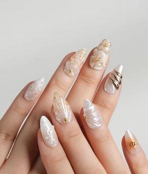 Golden Bay resort-luxe nails with milky white shimmer, shells, and gold florals