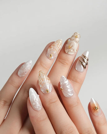 Golden Bay resort-luxe nails with milky white shimmer, shells, and gold florals