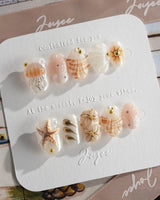 Golden Bay beach luxury nails with pearly white base, shells, and gold florals