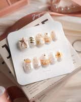 Golden Bay extra short squoval nails with shell accents and gold floral shine