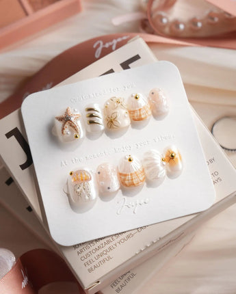Golden Bay extra short squoval nails with shell accents and gold floral shine
