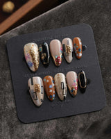 Golden Kiss L press-on nails in medium almond with hand-painted flowers and gold lines