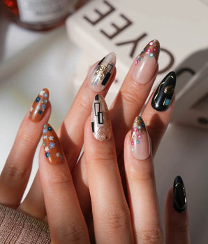Golden Kiss XS press-on nails in medium almond with raised gold spirals and black accents