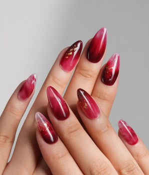 Close-up of Gone with the Wind press-on nails with marbled burgundy and gold foil details