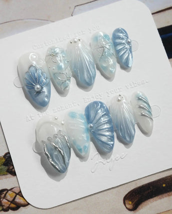 Great Barrier Blue medium almond nails with pearlescent shells, pearls, and silver chrome