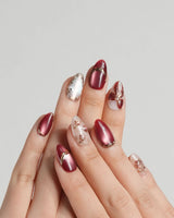 Coquette Red press-on nails with deep red chrome, nude base and gold bow accents