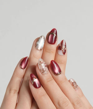Coquette Red press-on nails with deep red chrome, nude base and gold bow accents