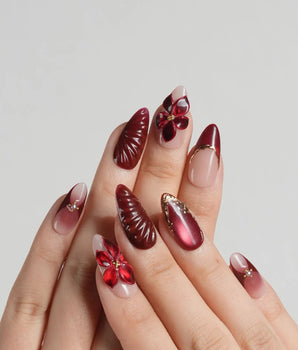 Lily Rouge press-on nails with red cat-eye French tips and gold outlined floral details