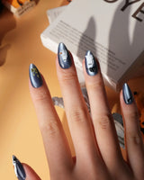 Ghost Errands press on nails with little white ghosts holding a pumpkin, a broom and an umbrella on slate blue cat eye - image 2