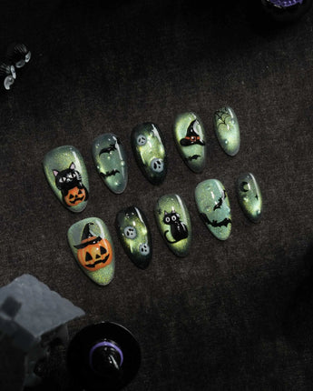 Witch's Cat press on nails with a black cat on a jack-o-lantern, witch hat, skulls, bats and a spider web on green shimmer cat eye - image 1