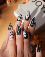 Cat Sitter press on nails with a long-tailed black cat, a row of bats and a white ghost holding a kitten on black and nude with pink shimmer - image 1