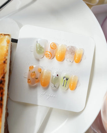 Iced Punch short oval press-on nails with warm orange jelly gradient and fruit charms