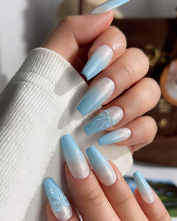 Macro detail of handmade baby blue nails with ombre and bow texture