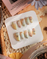 Close-up of Pastel Relic nails with pearly gradient, fine gold lines, and tiny starbursts