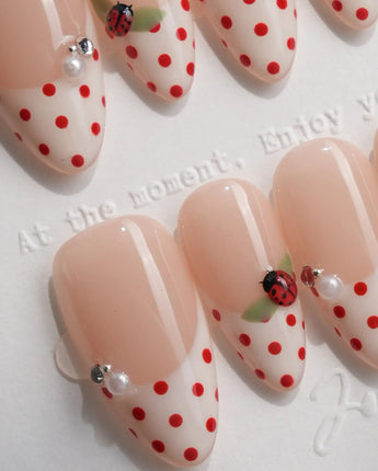 Close-up of retro polka dot press-on nails featuring hand-painted ladybug details with pearl embellishments