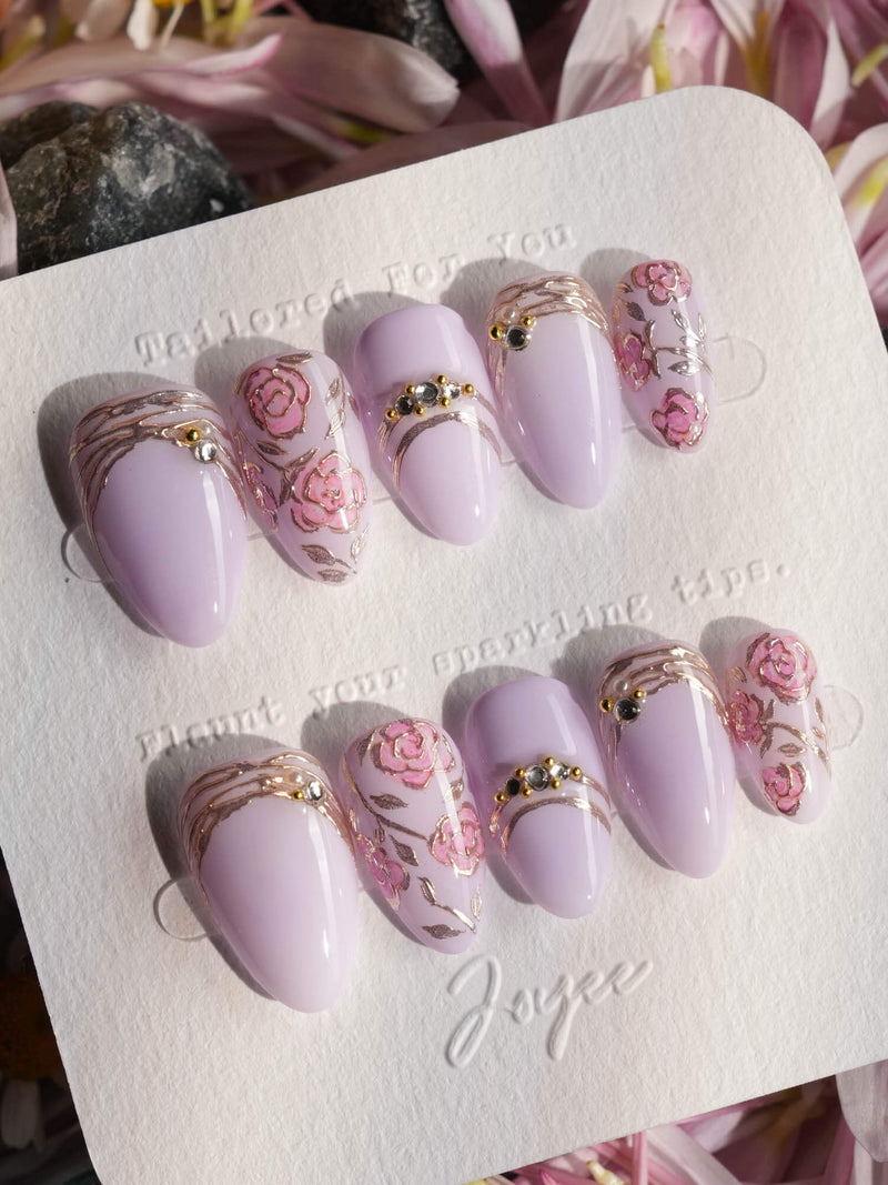 Ongles press-on faits main Lavender Rose avec de rêveuses roses violet clair peintes à la main aux contours métalliques sur forme amande extra-courte — nail art facile et élégant pour débutants