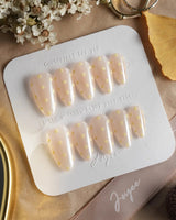 Lemon soda press-on nails with soft vanilla yellow, pearly nude glow and white polka dots