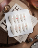 Little Luck press-on nails in medium stiletto shape — milky white red heart nails