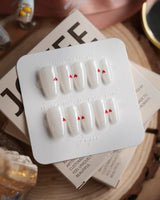 Little Luck press-on nails in short coffin shape — milky white red heart nails