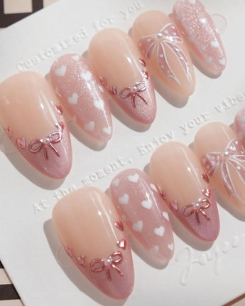 Love Letter handmade press-on nails featuring Dreamy Shimmer Pink, 3D Metallic Bows, White Hearts & Hand-painted Ribbons.
