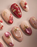 Close-up of Crystal Berry press-on nails with red cat-eye cherries, gold outlines and glossy 3D details