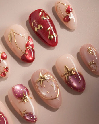 Close-up of Crystal Berry press-on nails with red cat-eye cherries, gold outlines and glossy 3D details