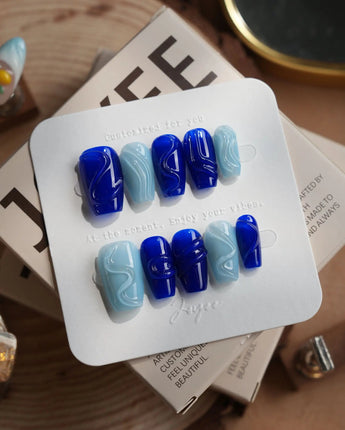 Majorelle Blue short coffin nails with sculpted blue swirls and pearl shell details