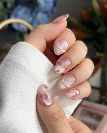Meadow Glow countryside charm nails with pastel pink base and small red blossoms