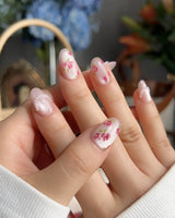 Meadow Glow garden picnic nails with bright floral print, pearls, and glossy pink finish