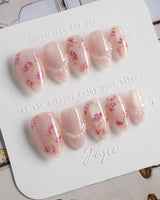 Meadow Glow extra short almond nails with soft pink flowers and delicate pearl chain