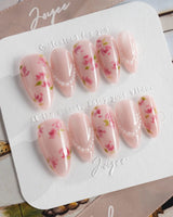 Meadow Glow medium almond nails with pink florals, pearl details, and summer bloom styling
