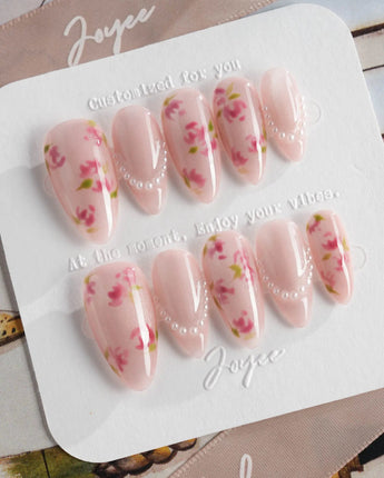 Meadow Glow medium almond nails with pink florals, pearl details, and summer bloom styling