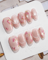 Meadow Glow short coffin nails with pastel floral art and small pearl accents