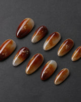 Onyx Shine press-on nails with amber marble color, black depth, and glossy gel finish