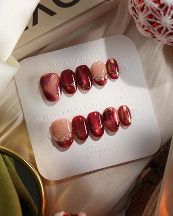 Molten Rouge press-on nails with molten red cat-eye gel, nude base and gold crystal accents