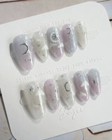Moonrest celestial manicure with soft pink glow, white fade, and glitter stars