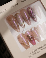 Close-up of Neon Kiss press-on nails with pink chrome butterfly wings, pearls and raised gold lines