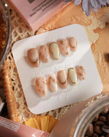 Earthy glow press-on nails with nude peach base, gold foil and delicate leaf accents