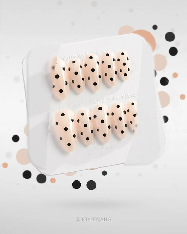 Nude press-on nails with black polka dots